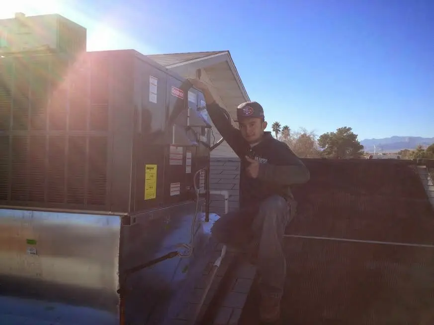 HVAC technician performing AC Tune-Up on a rooftop unit in DeWitt